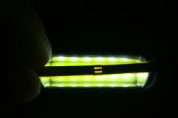 Pasek LED NeoPixel świecący na żółto-biało, częściowo zasłonięty palcami