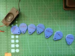 Speaker and RFID tags arranged on cutting mat Speaker and seven blue RFID tags with handwritten codes on a green cutting mat
