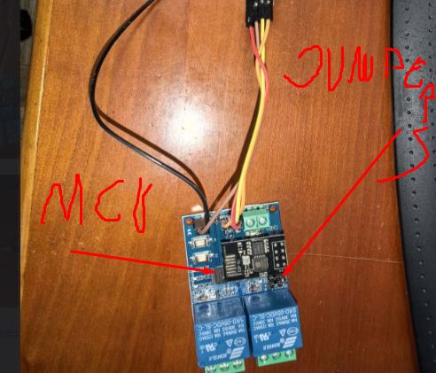 Relay module on a wooden desk with connected wires and red handwritten annotations