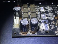 Zdjęcie uszkodzonego obwodu drukowanego z wylanymi kondensatorami elektrolitycznymi.