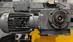 Silnik elektryczny i przekładnia zamocowane na metalowej konstrukcji przemysłowej.
