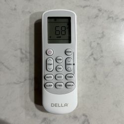 DELLA remote control with LCD display lying on a light marble surface.