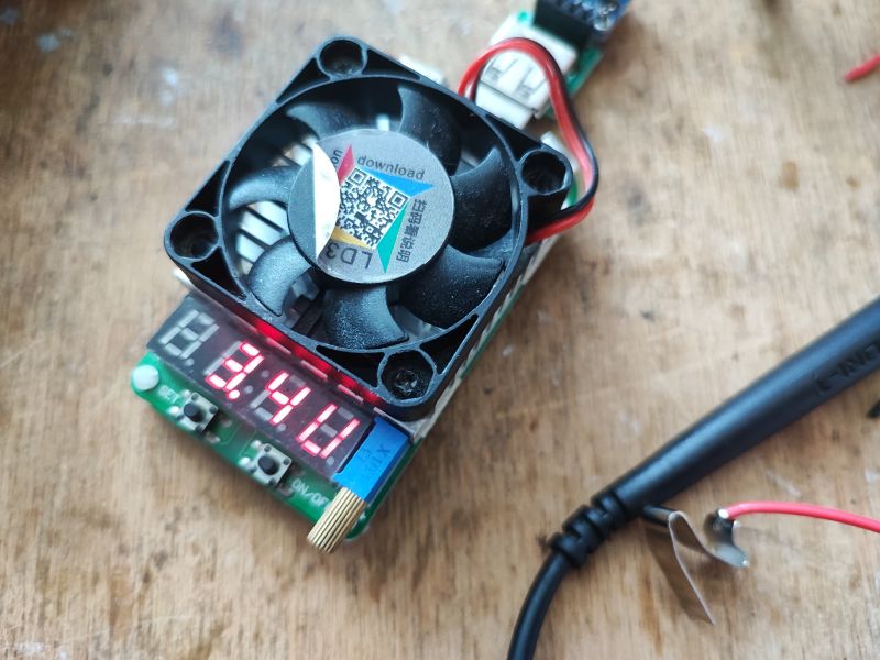 Elektroniczne sztuczne obciążenie z wyświetlaczem pokazującym 3.4V i wentylatorem chłodzącym.