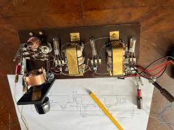 Amatorski odbiornik radiowy z tranzystorami ostrzowymi i schematem na kartce.