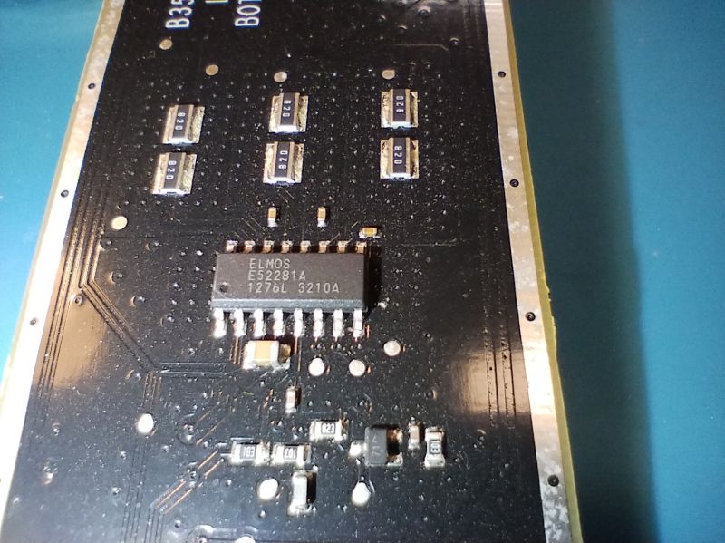 Zbliżenie na czarną płytkę PCB z układem scalonym Elmos E52281A i kilkoma innymi elementami elektronicznymi.
