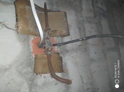 Przewody elektryczne zamocowane do muru za pomocą prowizorycznego mocowania.