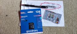 Packaging of a 128GB microSD card, a pen, and an envelope on the floor.