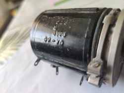 Zbliżenie czarnego cylindrycznego elementu Telpod z wytłoczonymi oznaczeniami i metalowym obejmem