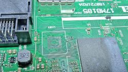 Zbliżenie PCB z polem lutowniczym BGA po usuniętym układzie, obok złącze i duży układ scalony.