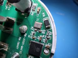 Close-up of a green PCB with an IC, SMD components, and “RM‑SMART” markings.