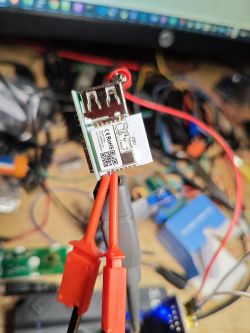 Close-up of an electronic module with a CBU chip, connected by red test leads with crocodile clips.