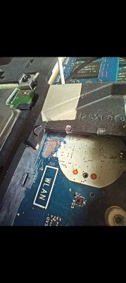 Zbliżenie na płytę główną Alienware m17x R1 z odsłoniętym polem opisanym WLAN i widocznymi ścieżkami obok miejsca po oderwanym gnieździe baterii BIOS.