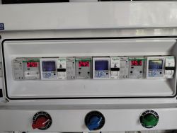 Panel elektryczny z trzema licznikami energii i trzema wskaźnikami napięcia pokazującymi wartości 250V, 245V oraz 251V.