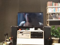 Pokój z akustycznym pokryciem ścian, telewizorem i sprzętem audio.