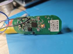 Green PCB with wires, ICs, and a lit orange LED on a blue work mat
