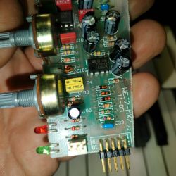 Płytka drukowana z różnymi komponentami elektronicznymi, trzymana przez osobę.
