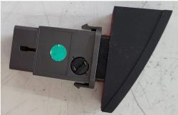 Przełącznik świateł awaryjnych z zieloną naklejką i klipsami.