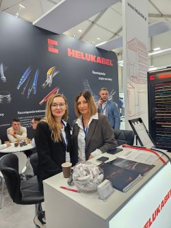 Stoisko firmy HELUKABEL z materiałami promocyjnymi i odwiedzającymi uczestnikami targów.