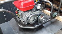 200cc Verbrennungsmotor mit rotem Kraftstofftank in einem Stahlrahmen eines Dreiradfahrzeugs montiert.