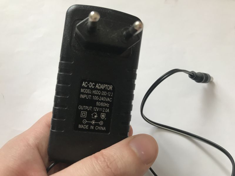 AC-DC power adapter 12V 2A with DC Jack plug held in a hand.