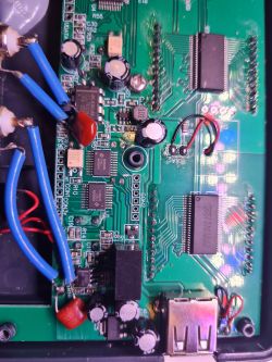 Close-up of a circuit board with visible electronic components such as capacitors, integrated circuits, and wires.