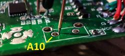 Close-up of a PCB with a probe pointing at a test pad labeled A10.