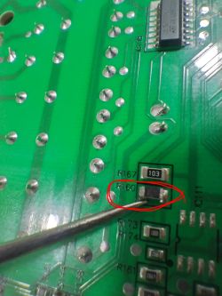 Highlighted resistor R160 on green PCB Close-up of PCB with resistor R160 circled and pointed to with a metal tool.