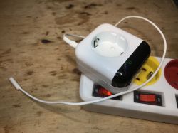 Electrical Socket with Temperature Sensor on Power Strip Electrical socket with a connected temperature sensor and wire, placed on a power strip.