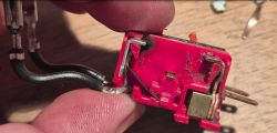 Disassembled microswitch with internal components exposed Close-up of disassembled red microswitch with visible wires and contacts