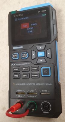 Ręczny miernik LCR z ekranem „calibration” i przewodem wpiętym w czerwone gniazdo
