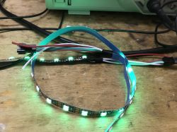 Connected LED Strip on Workbench Illuminated LED strip on a wooden table with connected wires.