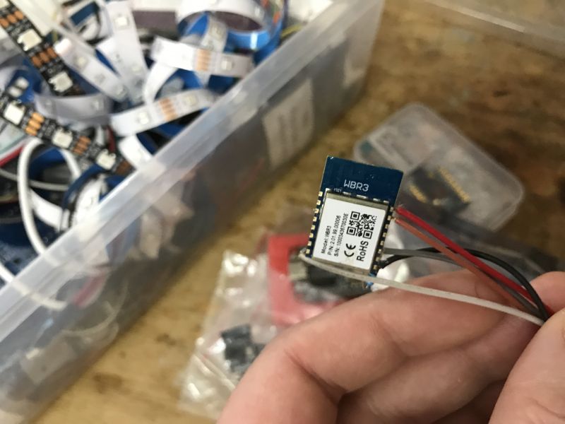 WBR3 module with wires held in hand against a background of a box with LED strips.