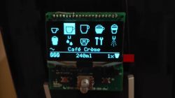 Kleines Display eines Kaffeeautomaten mit Getränke-Icons und dem Text Café Crème.