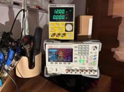 Two DC bench power supplies on a workshop shelf, both showing 12.00 V and 0.000 A