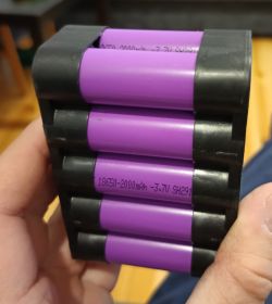 Ułożenie cylindrycznych ogniw równolegle w plastikowej obudowie trzymanej w ręce.