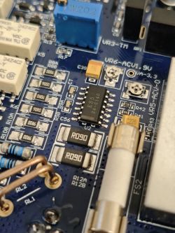 Zbliżenie na płytkę PCB multimetru z układem ES540, przekaźnikami, bezpiecznikiem i rezystorami R090