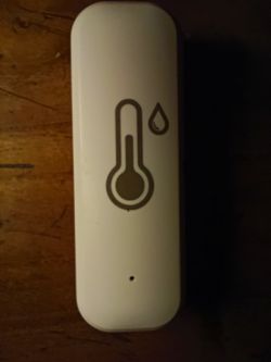White sensor with thermometer and droplet icon on wooden surface