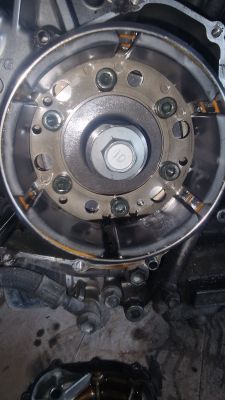 Zbliżenie na część mechanizmu silnika z widocznymi śrubami.