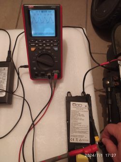 Multimetr mierzący napięcie podłączony do baterii hulajnogi FIAT 500.