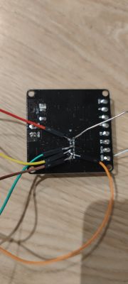 Black electronic board with soldered wires on wooden surface