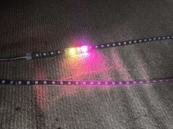Two LED strips on a carpet with several brightly lit bulbs of different colors.
