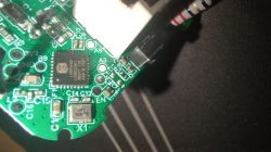 Close-up of a green PCB with an LSM9DS1 chip and a black probe touching solder pads.