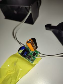 Zbliżenie na płytkę drukowaną z elementami elektronicznymi na tle obudowy reflektora.