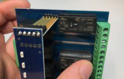 A person holds a circuit board with HF115FK relays and screw terminals.