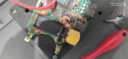 Uszkodzona płytka elektroniczna z widocznym przewodem i żółtym elementem.