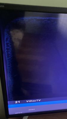Ciemny ekran telewizora Sharp z niebieskawą poświatą i jasnymi plamami wzdłuż lewej i górnej krawędzi ekranu.