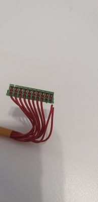 Zbliżenie na zielone złącze elektryczne z wieloma czerwonymi przewodami.