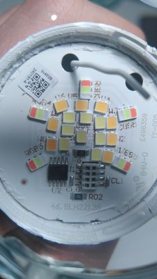 Close-up of a circuit board with multicolored LEDs and two wires connected at the top.