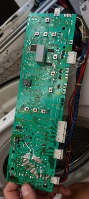 Płytka elektroniki pralki trzymana w dłoni.
