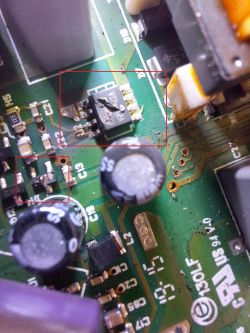Zbliżenie na uszkodzoną płytkę elektroniczną z widocznymi komponentami.